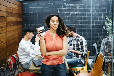 Portrait of smiling young woman standing against wall