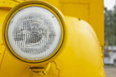 Fragment with headlight of yellow retro car outdoors, and close up. vintage automobile.