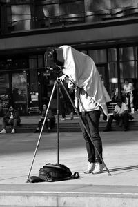 Man photographing while standing on street in city