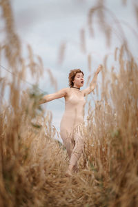 Woman with arms raised standing on field