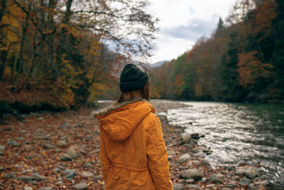 Rear view of person standing on rock during autumn