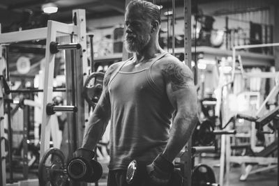 Mature man exercising with dumbbells in gym