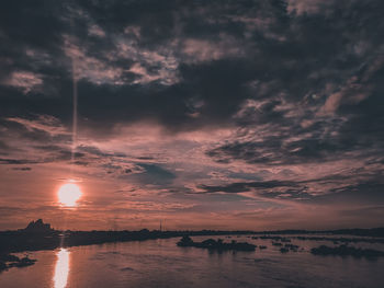 Scenic view of lake against dramatic sky during sunset