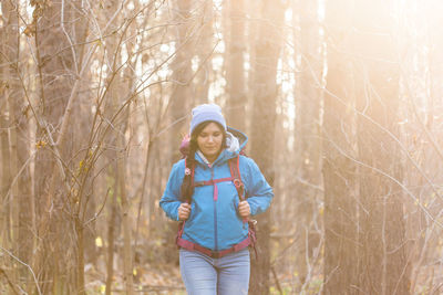 Portrait of smiling girl standing by tree in forest