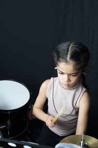 Girl wearing hearing aid while playing drum against wall