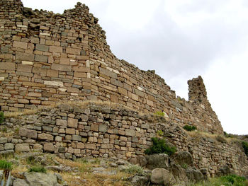 Low angle view of stone wall against sky