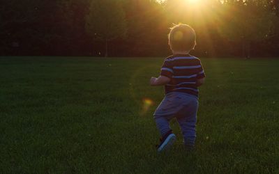 Rear view of boy walking on field