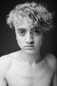 Portrait of shirtless boy against black background