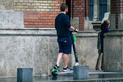 Rear view of people on skateboard against wall