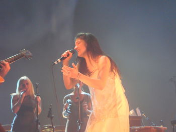 Young woman with arms raised standing at music concert