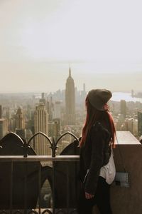 Woman looking at cityscape against sky