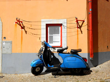 Blue moped parked against building in bright sunshine. lisbon portugal.
