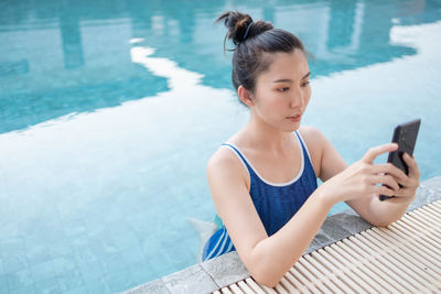 Young woman using mobile phone in swimming pool
