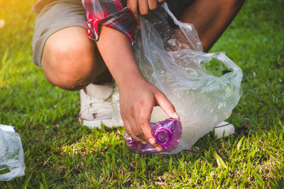 Low section of person collecting garbage on grassy field