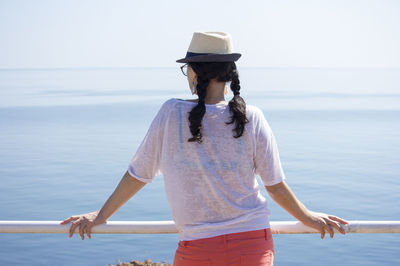 A woman is leaning on the railing and looking at the sea