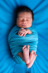 Directly above shot of cute baby wrapped in blanket sleeping in bed at home