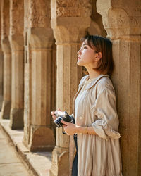 Side view of young woman looking at camera