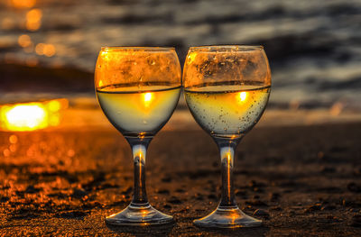 Close-up of wineglass on table during sunset