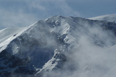 Scenic view of snowcapped mountains against cloudy sky