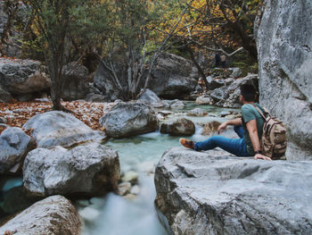 Man sitting on rock by river