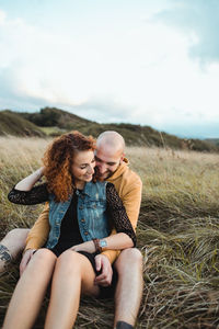 Happy friends sitting on land against sky