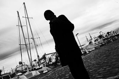 Man photographing at harbor against sky