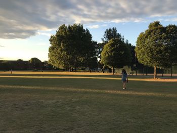 People playing soccer on field against sky