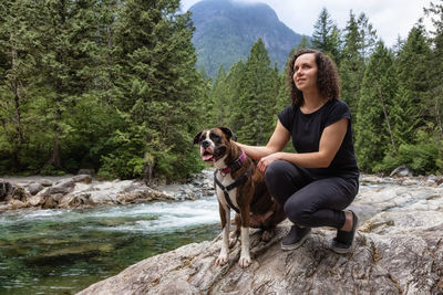 Young woman with dog sitting on rock