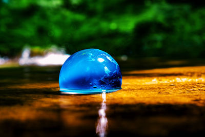 Blue glass globe on the water stream in golden sand