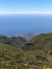Scenic view of sea and mountains against blue sky