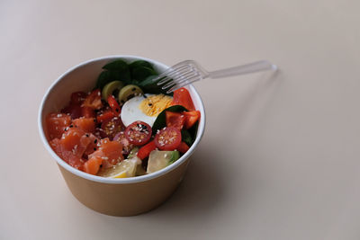 Takeaway poke bowl with fresh salmon, avocado,  vegetables in recycled kraft paper packaging. 