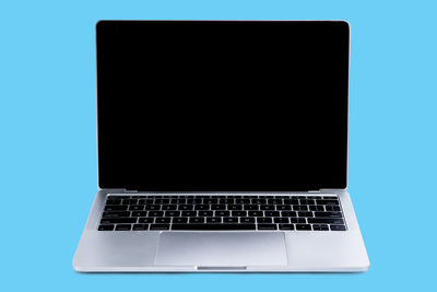 Close-up of laptop on table against blue background