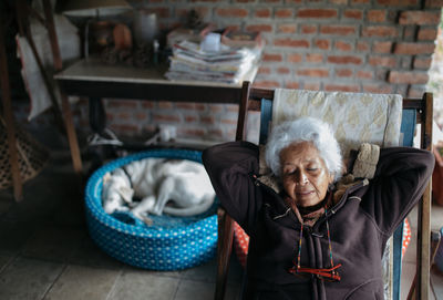 High angle view of senior woman relaxing on chair at home