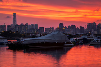 Scenic view of river and buildings against orange sky