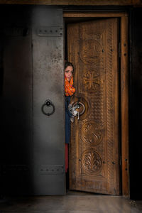 Portrait of woman standing against door of building