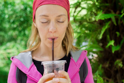Woman with eyes closed drinking outdoors