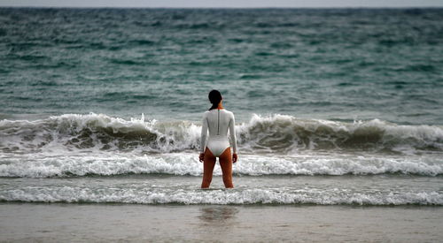 Rear view of young woman wearing swimwear while standing in sea