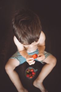 Midsection of man eating food against black background