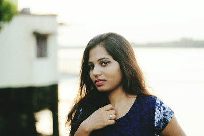 Thoughtful young woman standing against lake during sunset