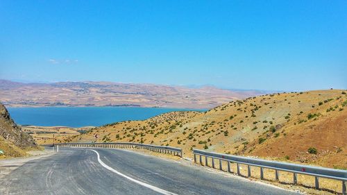 Scenic view of mountain road against clear blue sky