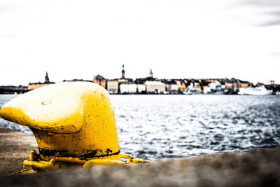 Close-up of yellow umbrella by sea against clear sky