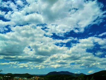 Low angle view of trees against cloudy sky