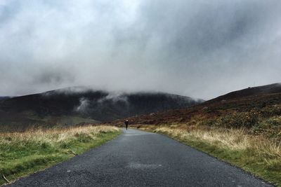 Country road against cloudy sky
