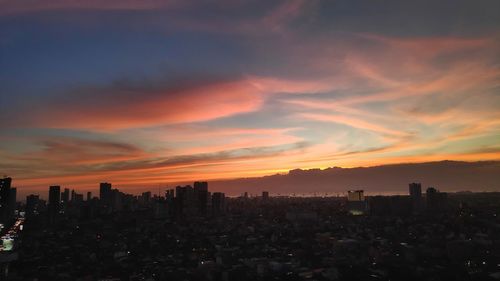 Buildings in city against romantic sky at sunset