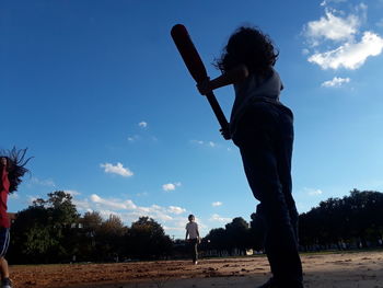 Rear view of boy standing by tree against sky