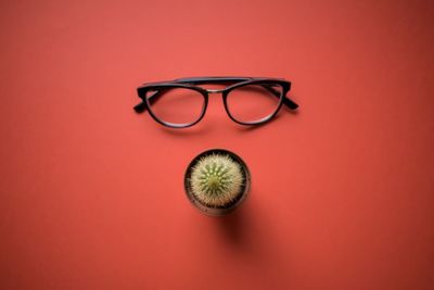 Close-up of eyeglasses on table against red background