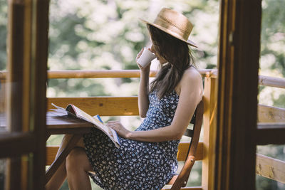 Woman drinking coffee and reading newspapers on balcony