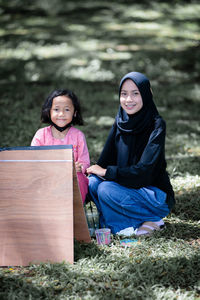 Portrait of young woman sitting on field