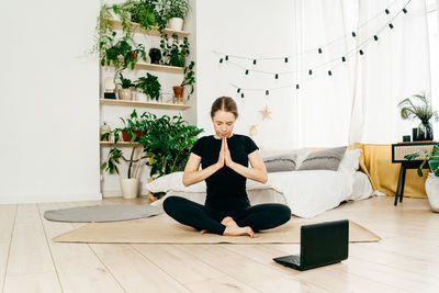 Portrait of woman sitting on potted plant at home