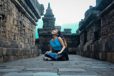 Full length of woman sitting against temple